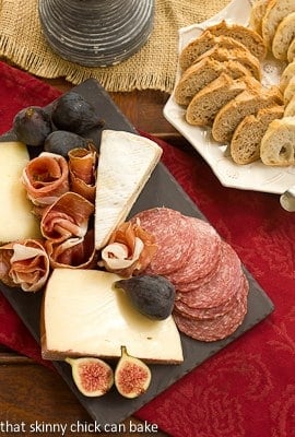 Overhead view of a meat and cheese tray next to a plate of bread.