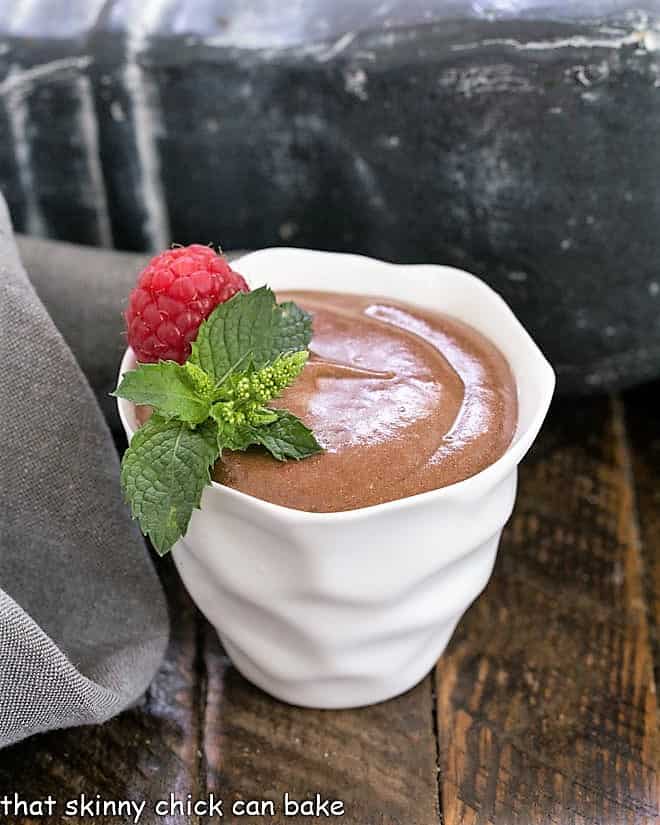 French chocolate mousse in a white bowl topped with a raspberry and mint