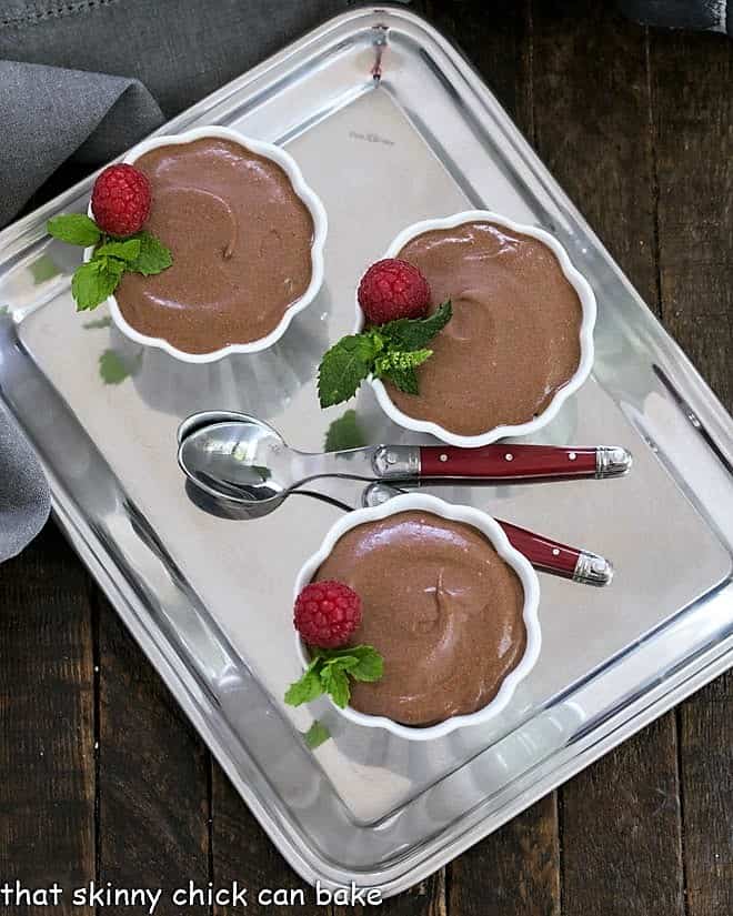 3 cups of chocolate mousse on a silver tray with two spoons