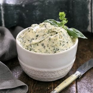 Basil butter in a white bowl with a small knife