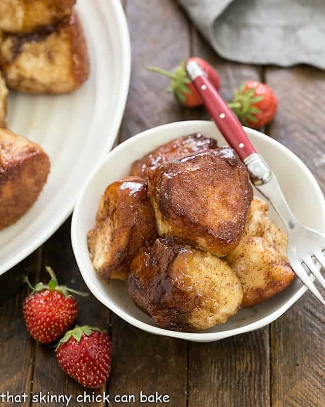This scrumptious Cinnamon Monkey Bread Recipe is an outstanding, 5-Alarm breakfast treat that will thrill your family! Bowl of monkey bread with a red handled fork.