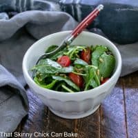 Bowl of massaged kale salad in a white salad bowl with a red handle fork