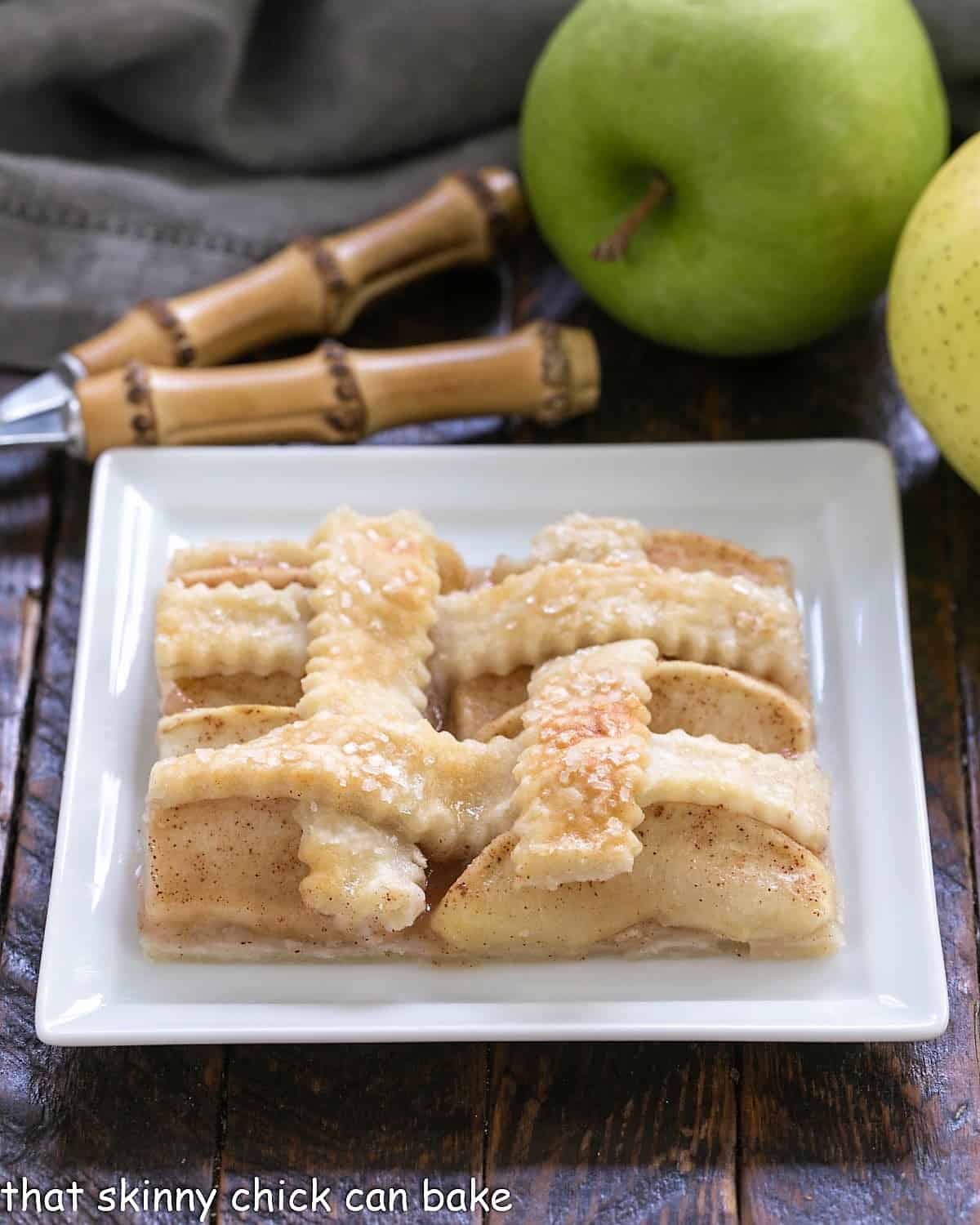 A slice of apple slab pie or apple squares on a square white plate.