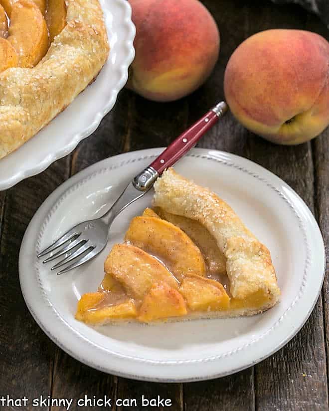 Slice of peach galette on a white plate with a red handle fork.