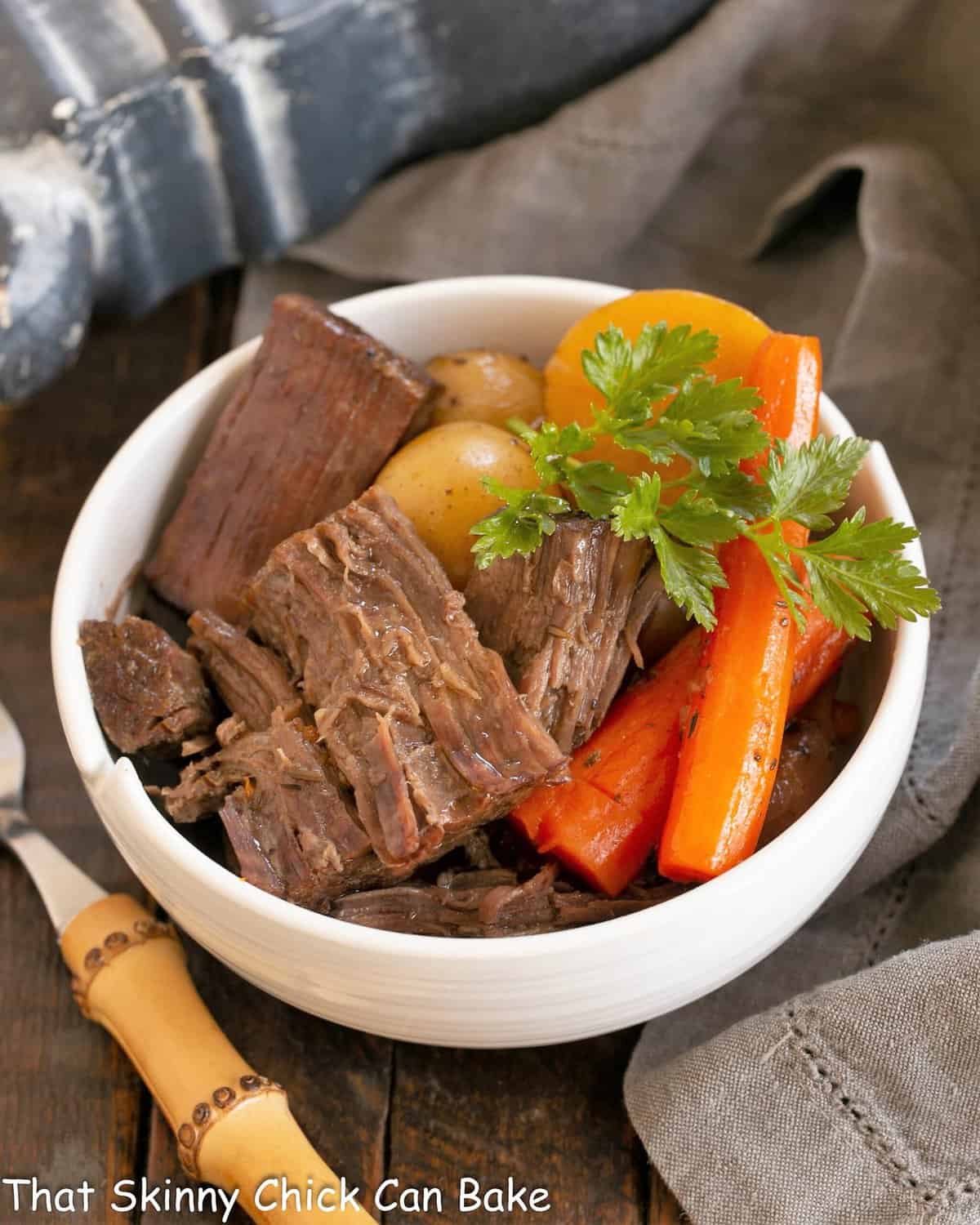 Pot roast garnished with parsley in a white bowl.