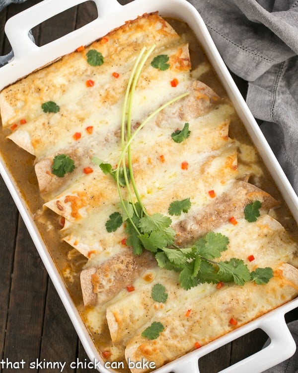 Cheesy Chicken Enchiladas in a white casserole dish with a garnish of cilantro