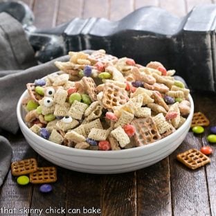 Side view of a shallow white bowl of Halloween Chex Mix