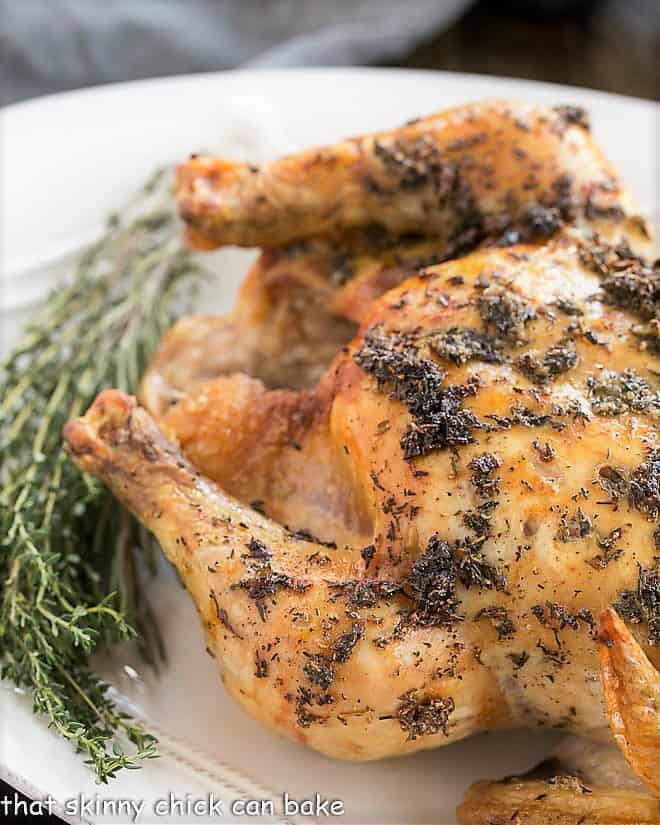 Whole Roasted Chicken on an oval platter garnished with thyme.