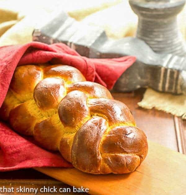 Pumpkin Challah wrapped in a red napkin on a cutting board.