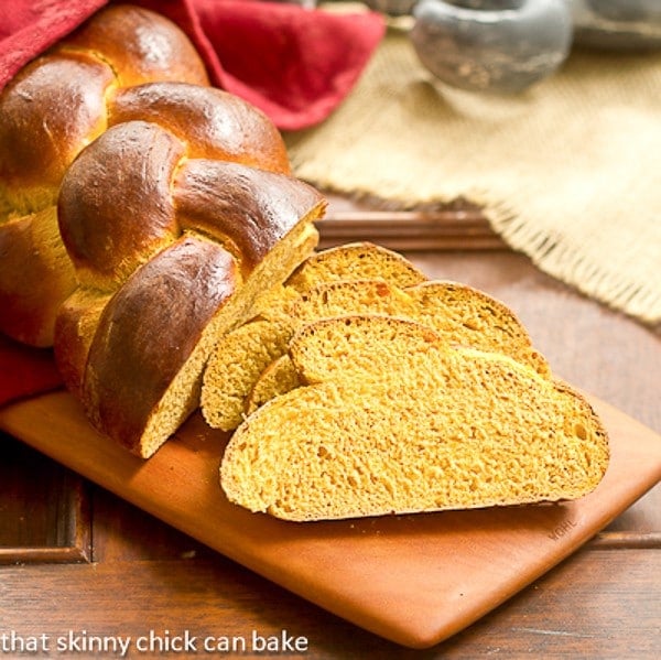 Pumpkin Challah slices on a wooden cutting board.