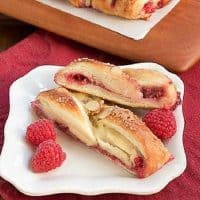 Raspberry Danish slices on a white plate with fresh raspberries