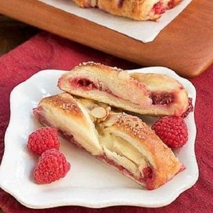 Raspberry Danish slices on a white plate with fresh raspberries