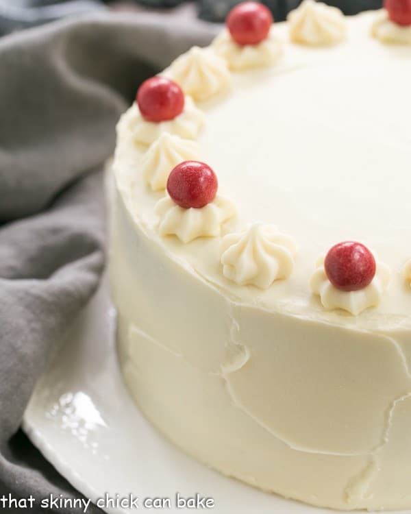 Red Velvet Cake with White Chocolate Cream Cheese Frosting on a white cake plate.