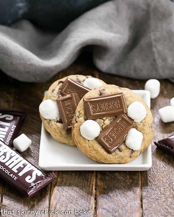 S'mookies AKA Gooey S'mores Cookies on a square white plate with mini Hershey bars