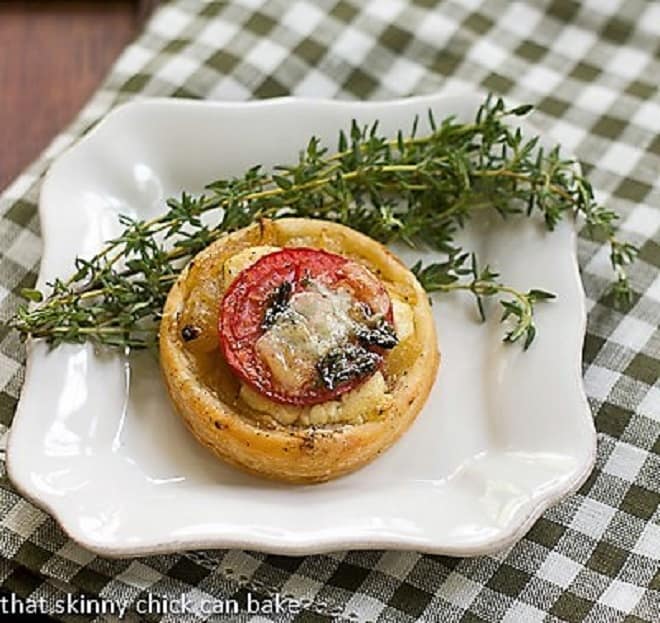 Tomato and Boursin Tartlet on a square white plate with fresh thyme.