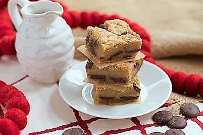 A stack of Caramel Chocolate Chip Cookie Bars on a white dessert plate