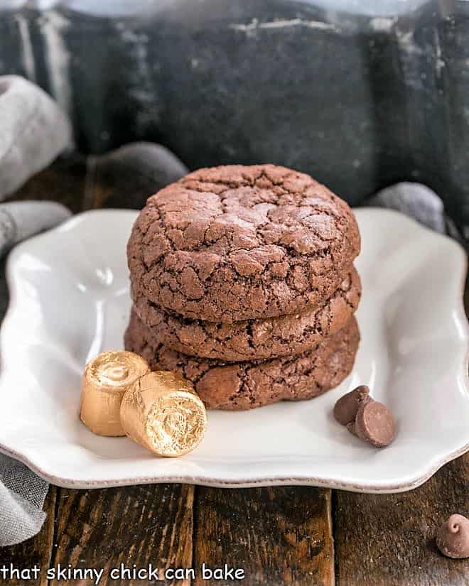 A stack of brownie cookies on a square white plate