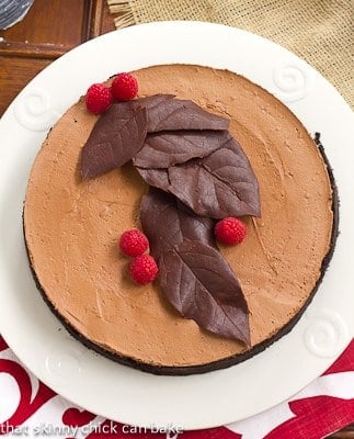 Chocolate Moussecake overhead view on a white platter topped with chocolate and berries.