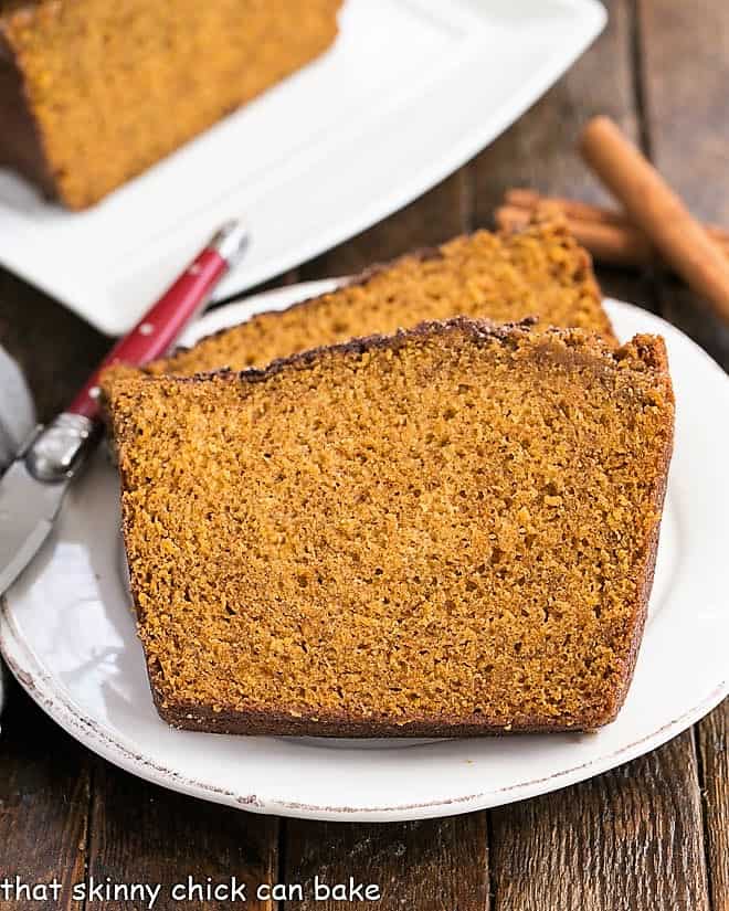 Two slices of cinnamon topped pumpkin bread on a white plate
