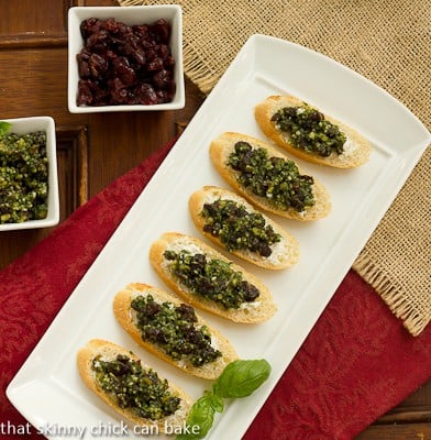 Cranberry Pesto Goat Cheese Crostini - an unusual, easy appetizer with a cranberry basil pesto and goat cheese on toasts! Overhead view of Cranberry Pesto Goat Cheese Crostini on a white ceramic tray