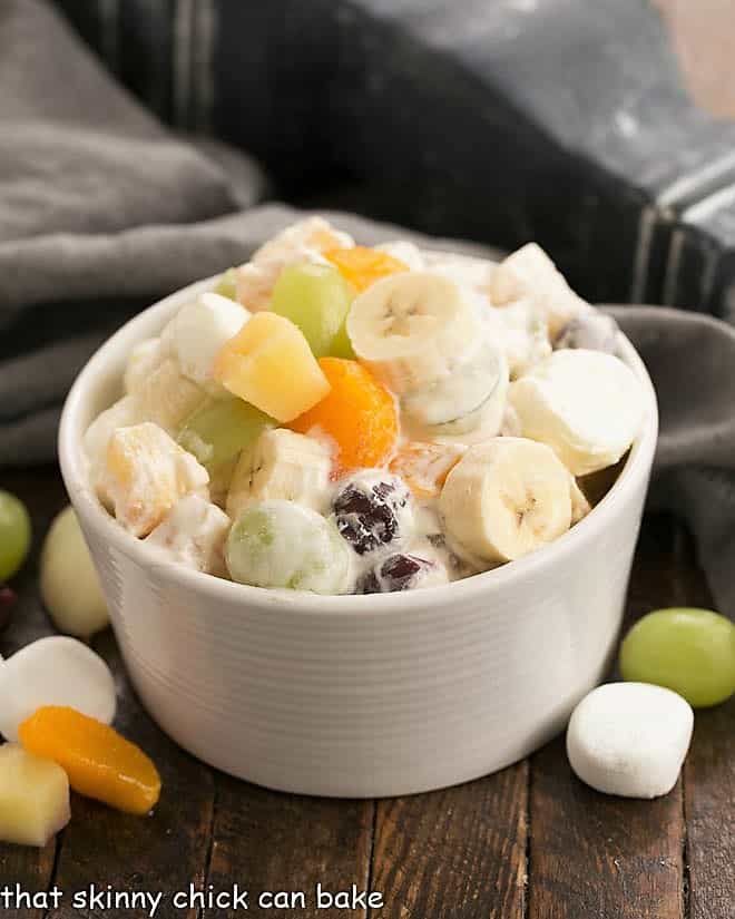24 hour fruit salad in a white bowl garnished with fruit and marshmallows