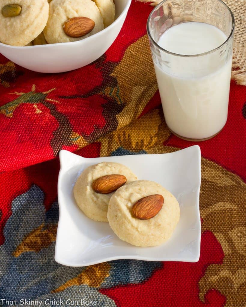 Overhead view of Ghraybeh or Lebanese Shortbread Cookies on a small white plate with a glass of milk