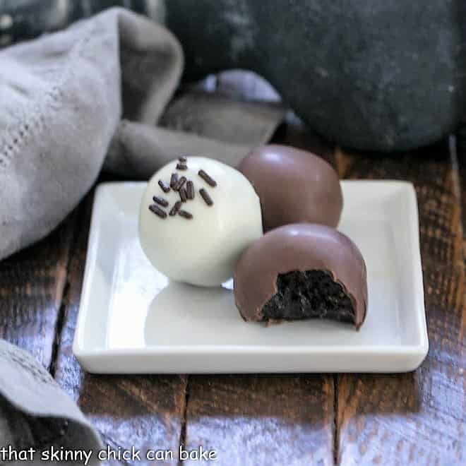 Oreo truffles on a plate with one showing the interior.