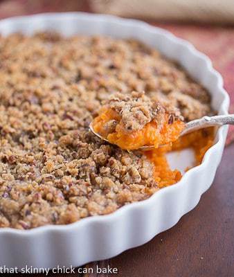 Praline Topped Sweet Potato Casserole in a round white baking dish with a spoonful removed.