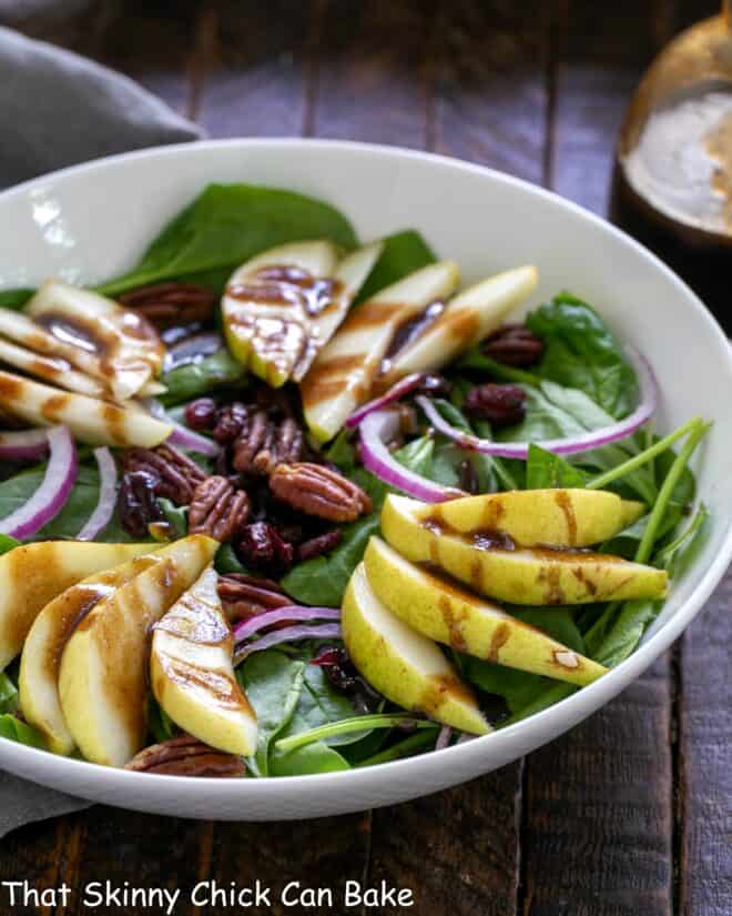 White bowl with spinach pear salad.