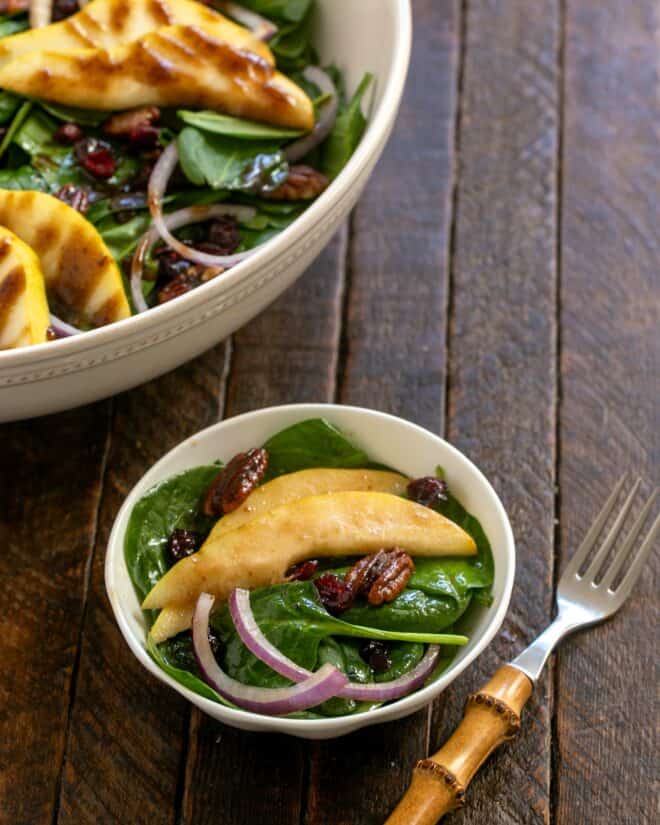 Serving of spinach and pear salad with a bamboo handled fork.