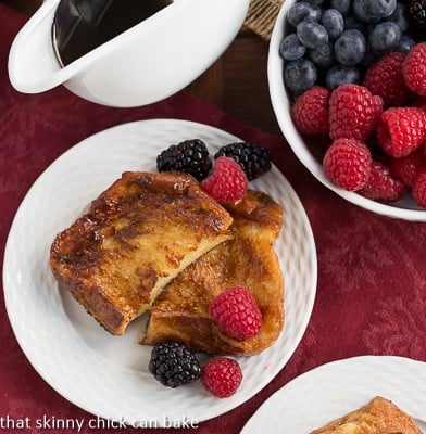 Overhead view of Sugar-Crusted French Toast on a white ceramic plate with fresh berries.