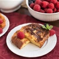 Sugar-Crusted French Toast cut in half and garnished with berries and mint on a white plate