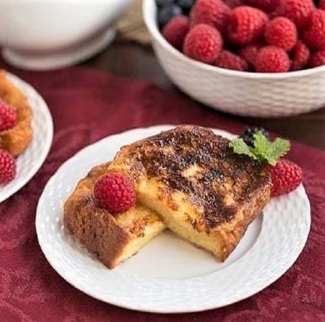 Sugar-Crusted French Toast Recipe cut in half and garnished with berries and mint on a white plate.