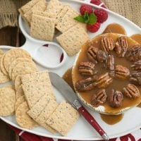 cheese tray with a wheel of baked Camembert topped with caramel sauce and pecans