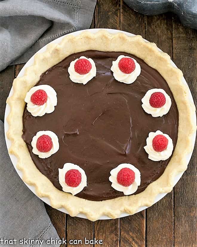 Overhead view of Chocolate Pie in a white pie dish topped with cream and berries.