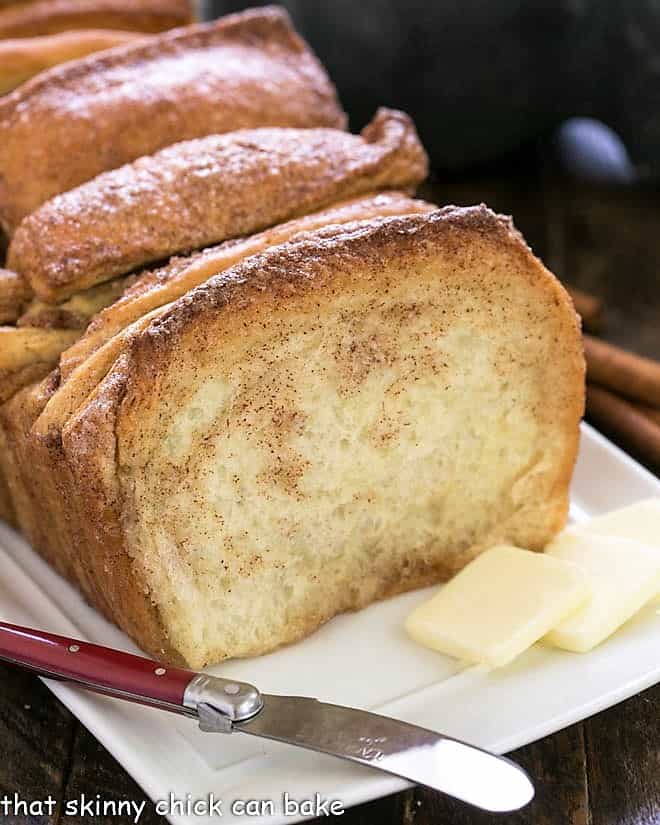 Cinnamon Pul Apart Bread on a white tray with a knife and butter pats
