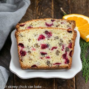 Two slices of cranberry orange bread on a square white plate