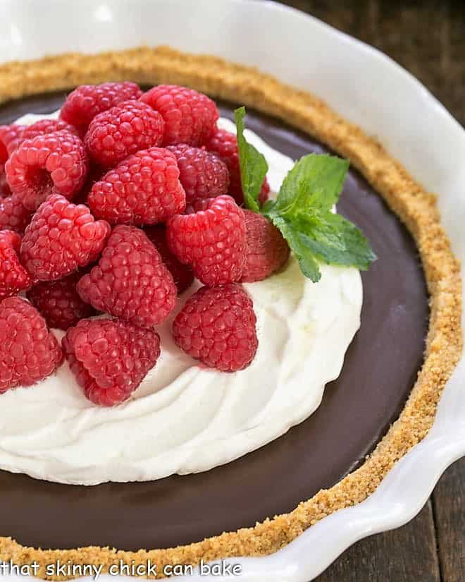 Close view of the chocolate pie topped with whipped cream and berries and garnished with a sprig of mint