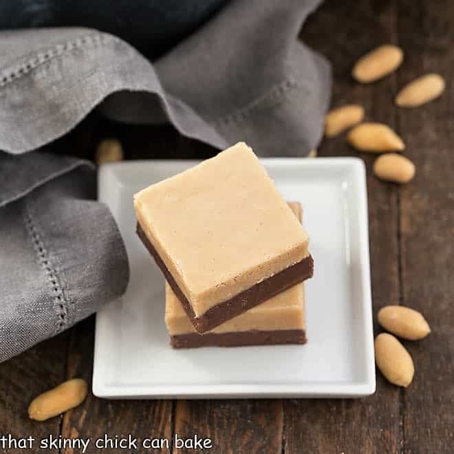 Two slices of Layered Chocolate Peanut Butter Fudge on a square white plate.