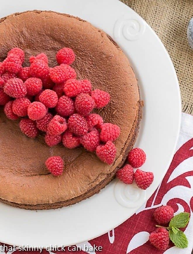 Overhead view of Chocolate Mousse Torte on white ceramic serving plate topped with fresh raspberries