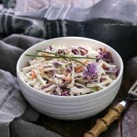 Cabbage slaw in a white bowl with a bamboo handle fork