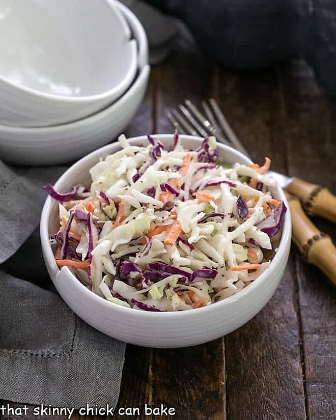 KFC coleslaw recipe in a white bowl with two spare bowls in the background.