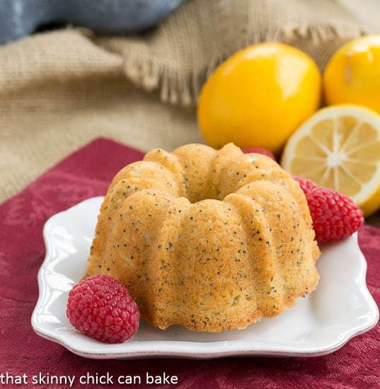 Meyer Lemon Poppy Seed Tea Cake on a white plate garnished with raspberries.