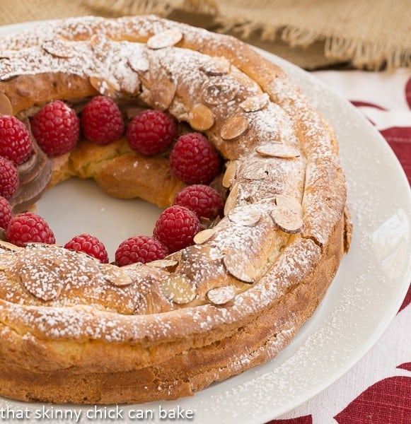 Paris-Brest garnished with raspberries on a white serving plate.