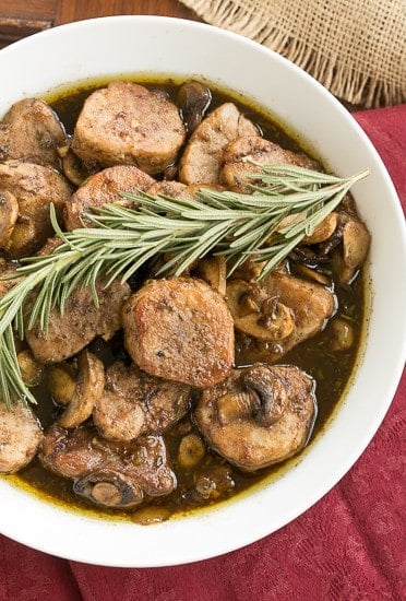 Pork Tenderloin Medallions in a white serving bowl topped with a sprig of rosemary.