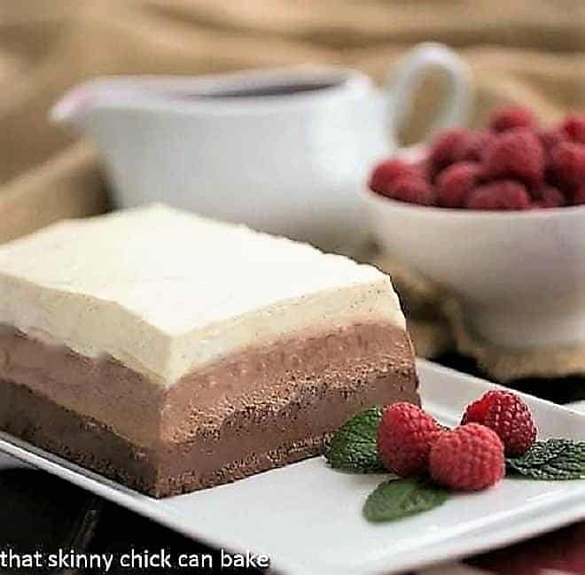 Triple chocolate terrine on a white platter with raspberries and mint