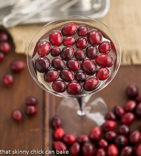 White Cosmopolitans in a martini glass topped with fresh cranberries.