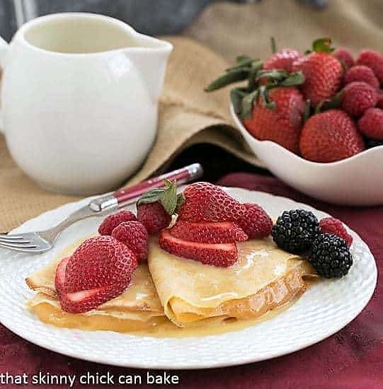 Butter and Rum Crêpes on a white plate topped with fresh berries