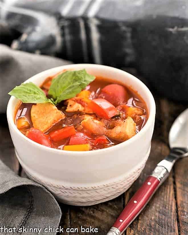 Chicken and Bell Pepper Chili in a small white bowl garnished with basil.