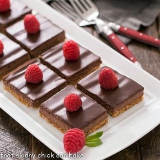 dark chocolate mousse bars topped with raspberries on a white ceramic tray
